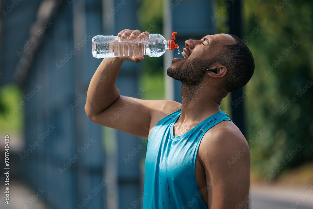 Well-built handsome sportsman drinking water after workout Well-built handsome sportsman drinking water after workout
