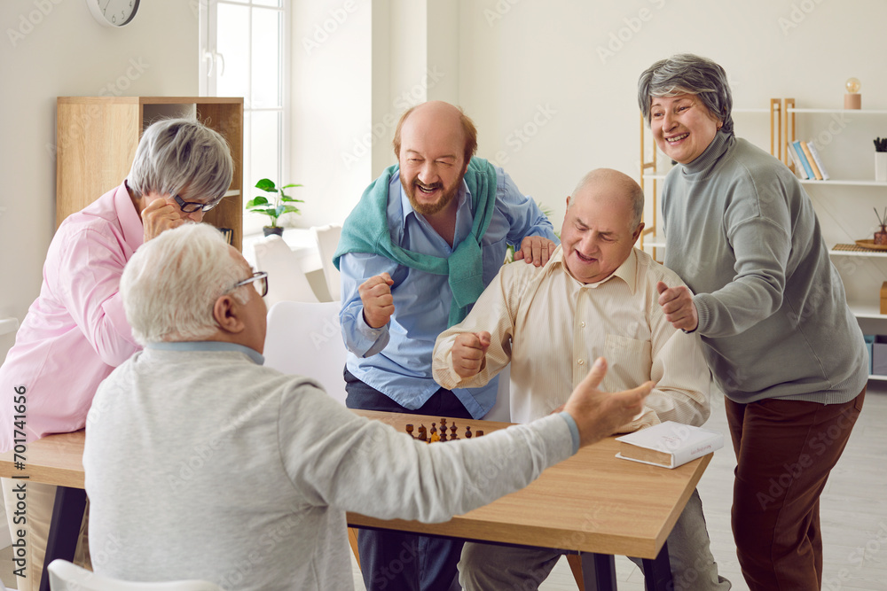Group of happy overjoyed senior people playing chess in nursing home sitting at the table. Retired men and women spending time together playing board games. Leisure in retirement home concept. Group of happy overjoyed senior people playing chess in nursing home sitting at the table. Retired men and women spending time together playing board games. Leisure in retirement home concept.