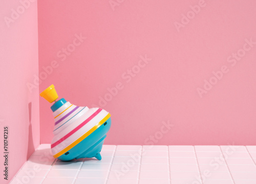Colorful fun spinning top on a pink background. Copy space for text.