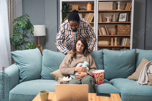 Mixed race couple African American man and white woman, male massage his girlfriend or wife in her menstrual period while sitting at home. Love, support and respect in relationship or marriage concept photo