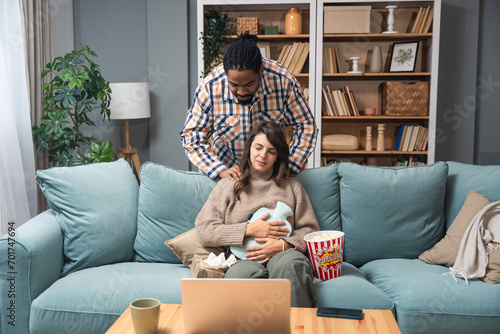 Mixed race couple African American man and white woman, male massage his girlfriend or wife in her menstrual period while sitting at home. Love, support and respect in relationship or marriage concept