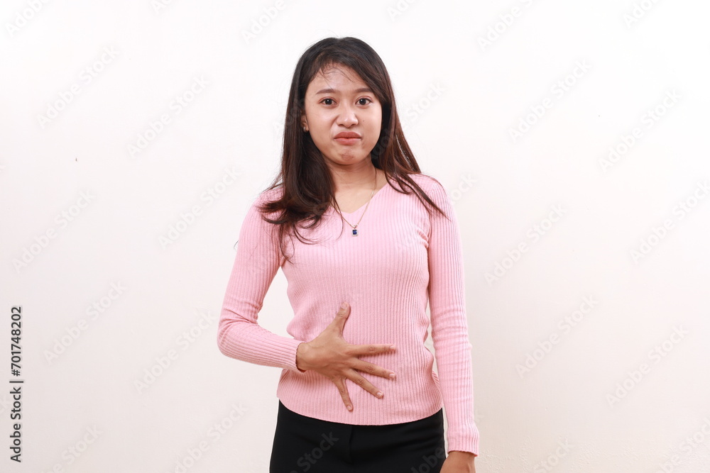 Young asian woman holding her stomach, feeling hungry with funny expression. Isolated on white Young asian woman holding her stomach, feeling hungry with funny expression. Isolated on white
