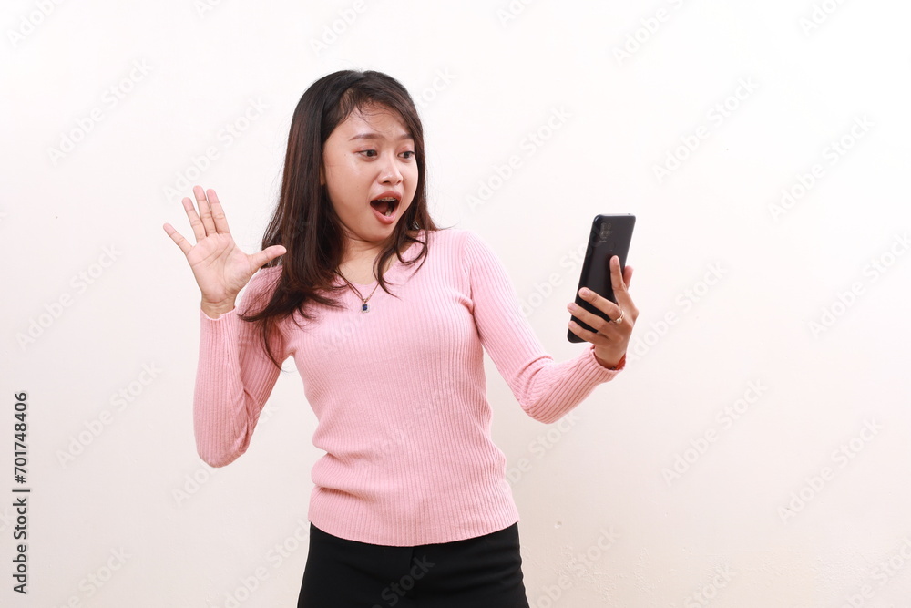 Wow excited young asian girl standing while holding a cell phone. Isolated on white background Wow excited young asian girl standing while holding a cell phone. Isolated on white background