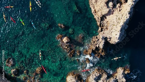 Aerial shot of kayak group tour exploring coastline of Mallorca, Spain. Drone view of kayakers paddle over coral reef and turquoise clear blue water. Fun sport activity for family on vacation photo