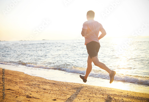Man running on the beach at sunset photo