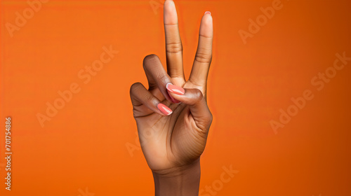 Hand with manicure isolated on orange background, V sign, Close up of african american woman hand, Female black hand showing two fingers, copy space photo