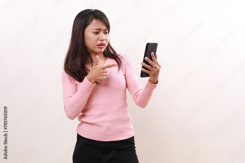 Confused young asian girl standing while received a message on her phone. Isolated on white background Confused young asian girl standing while received a message on her phone. Isolated on white background