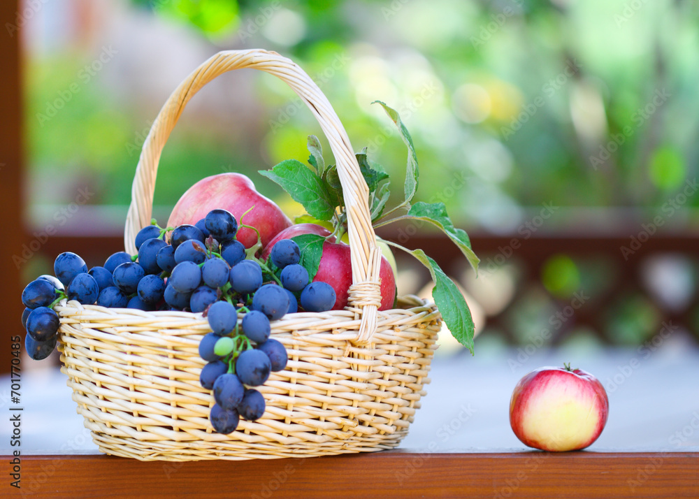 Tasty grapes and apples in the basket in the gazebo Tasty grapes and apples in the basket in the gazebo