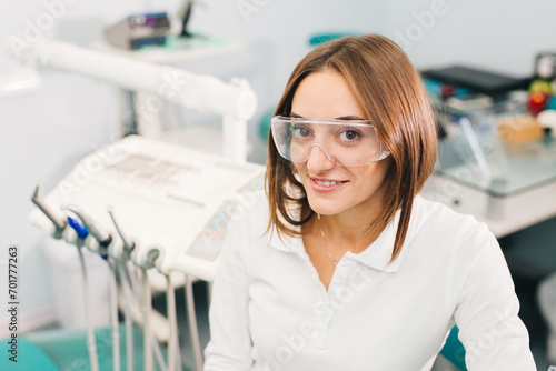 Young female dentist holds instruments in her hands in the interior of a modern dental clinic. The concept of professional activity, dental instruments and services.