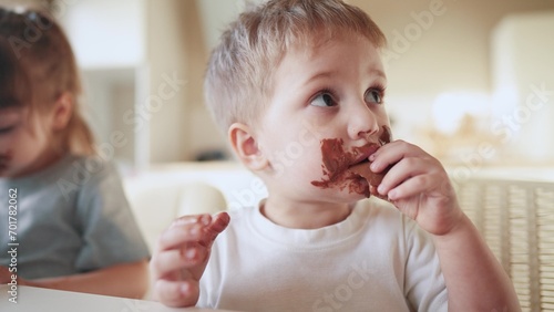 children eat chocolate. dirty little lifestyle baby kids in the kitchen eating chocolate in the morning. happy family eating sweets kid dream concept. baby dirty face eating chocolate cocoa