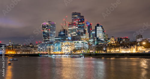 Night time panorama with the skyline of modern City of London, Thames river near tower castle with colorful illumination and water reflection. Capital of England with landmarks, sights at Tower Bridge
