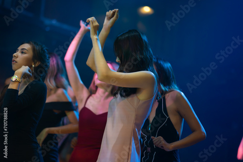 Sexy young woman people dancing and holding champagne glass in night club. Happy fun Asian people dance in night club. Nightlife and disco dance party concept. Fun music festival