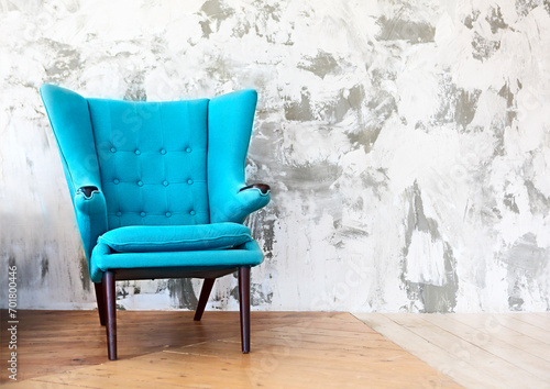 One blue armchair against a white and gray wall and floor