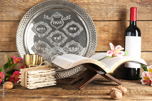 Torah, Passover Seder plate, flatbread matza, bottle of wine, alstroemeria flowers and walnuts on wooden background photo