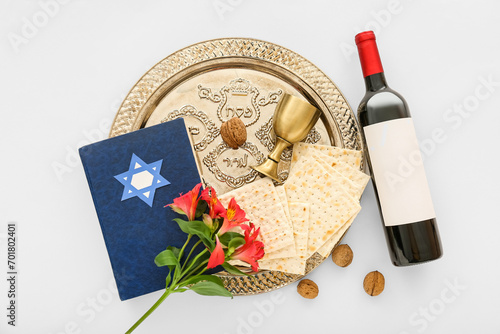 Passover Seder plate with flatbread matza, bottle of wine, Torah, walnuts and flowers on white background photo