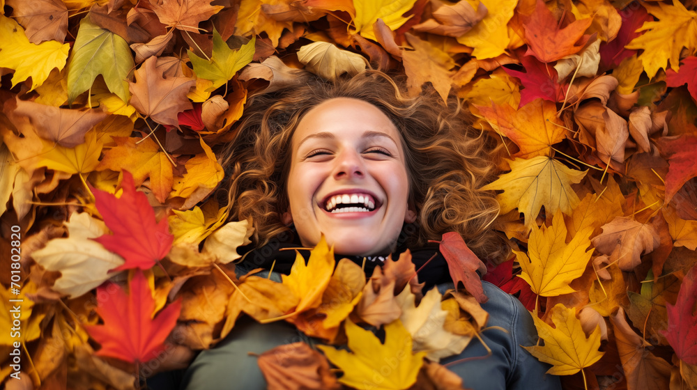 A laughing individual lying flat in a sea of multicolored autumn leaves