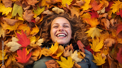 A laughing individual lying flat in a sea of multicolored autumn leaves