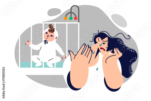 Crying mother experiences postpartum depression located near newborn baby sitting in crib