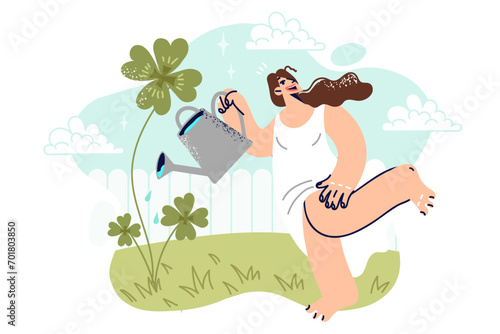 Woman waters yarrow clover in backyard, and smiles standing in short summer dress