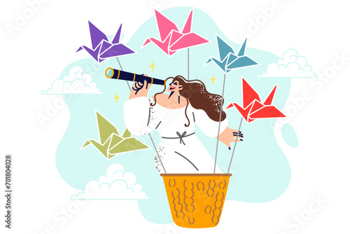 Woman fantasizes about traveling world and having new adventures flying in basket with origami swans