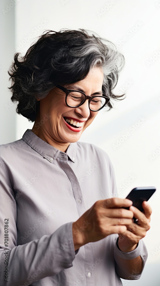 A senior woman looking at the smartphone and laughing closeup.