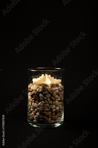 Seashells and starfish candles with stones in a glass on black background