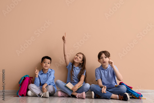 Little pupils pointing at something near beige wall photo