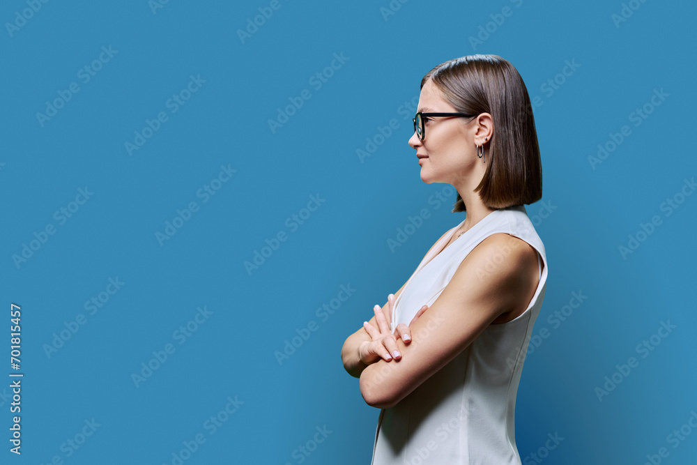 Profile view, confident young business woman, copy space blue studio background Profile view, confident young business woman, copy space blue studio background
