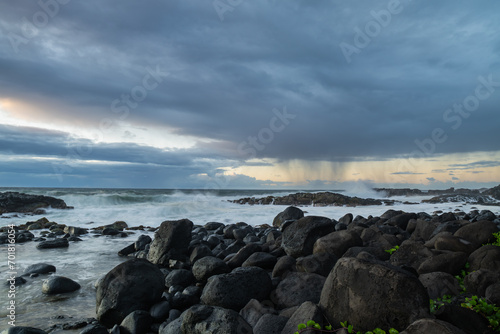 Long exposure view of waves crashing on the rocky shore of Benares beach during a rainy morning in Mauritius island