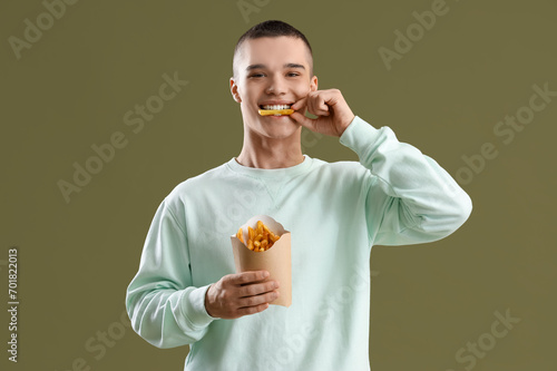 Young man eating french fri...