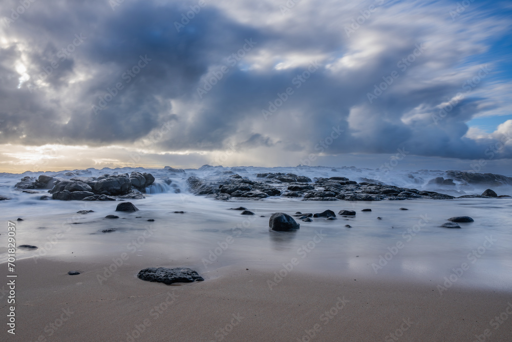 Fototapeta premium Long exposure view of waves crashing on the rocky shore of Benares beach located on the south coast of Mauritius island
