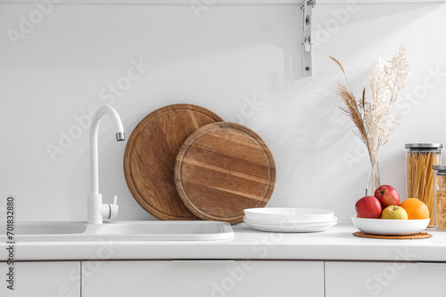 Fototapeta Naklejka Na Ścianę i Meble -  White counters with sink, fruits and wooden boards in interior of modern kitchen