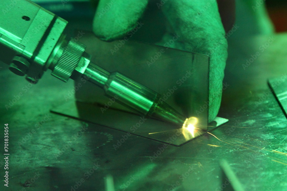 Laser beam welding of metal angle on welding table closeup. LBW assembly details View through the green safety glass