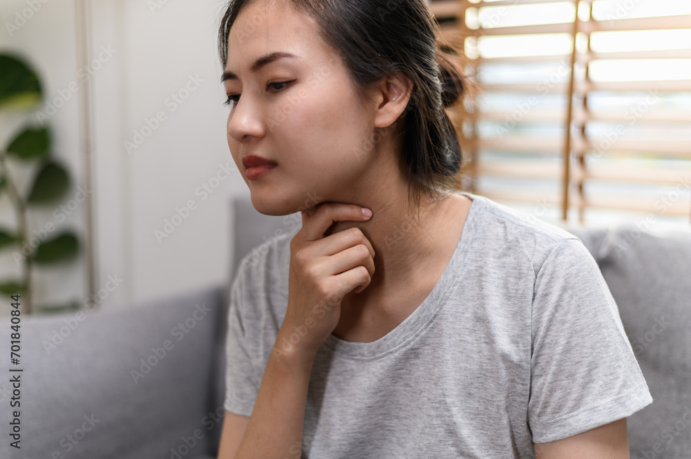 Young Asian woman have a sore throat or have a sick fever taking a medicine and drinking water while sitting on sofa at home. Young Asian woman have a sore throat or have a sick fever taking a medicine and drinking water while sitting on sofa at home.