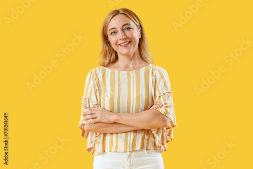 Mature woman smiling on yel...