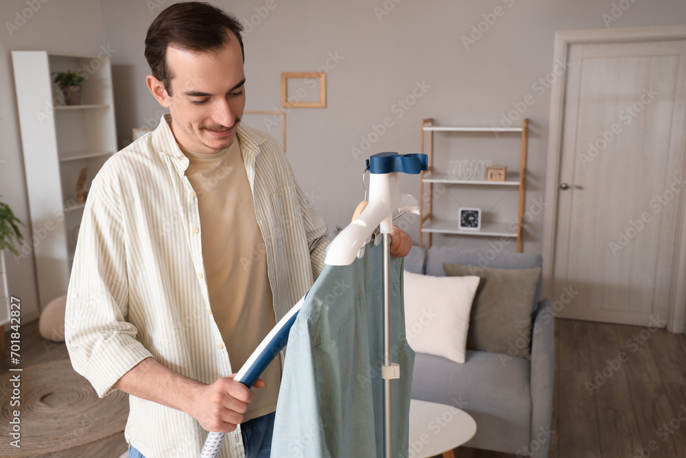 Young man steaming shirt at home Young man steaming shirt at home