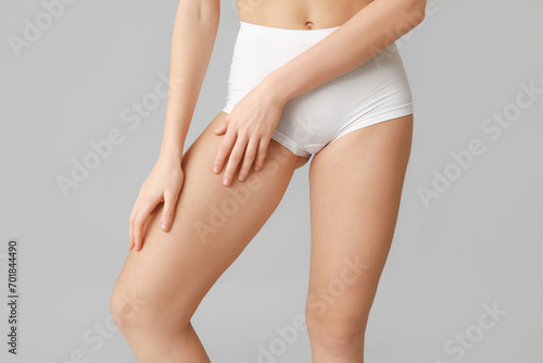 Beautiful young woman after depilation legs on grey background, closeup