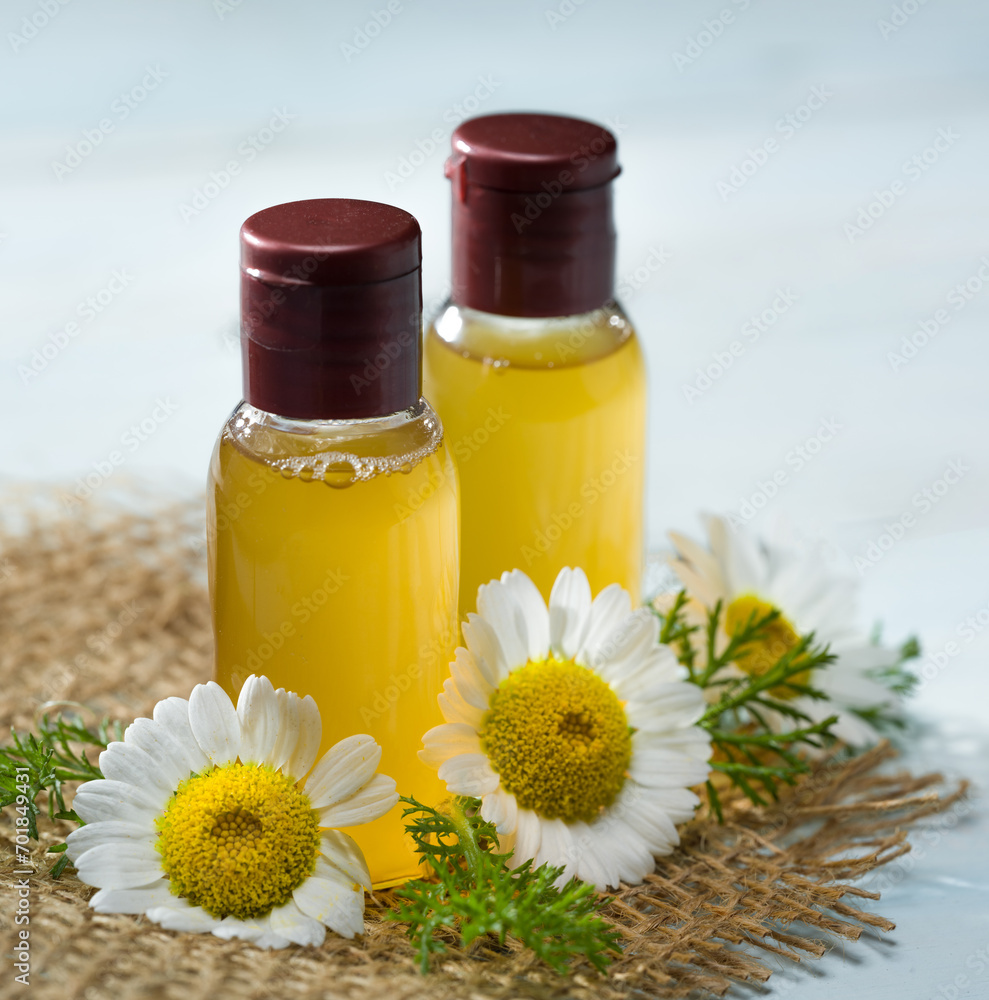 Two bottles of chamomile water with fresh chamomile flowers on the table Two bottles of chamomile water with fresh chamomile flowers on the table