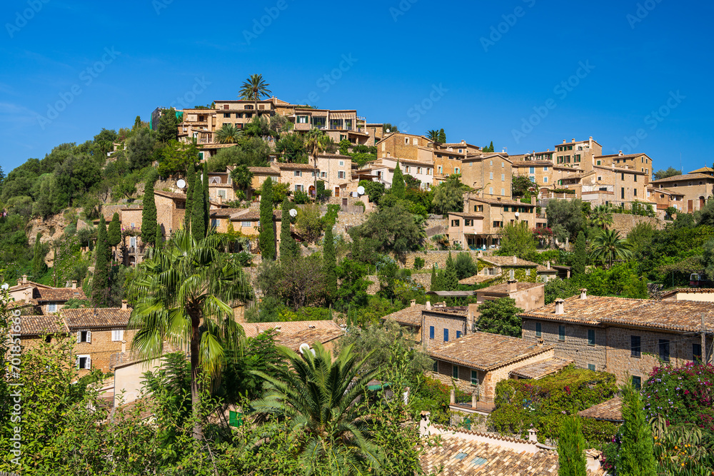 Stunning cityscape of the small coastal village of Deia in Mallorca, Spain. Traditional houses terraced on hills surrounded by green trees. Tourist destinations in Spain. Balearic Islands.