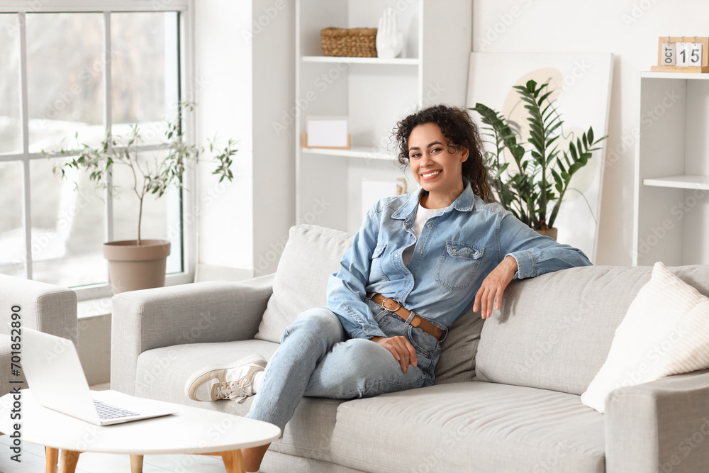 Young African-American woman sitting on sofa at home Young African-American woman sitting on sofa at home