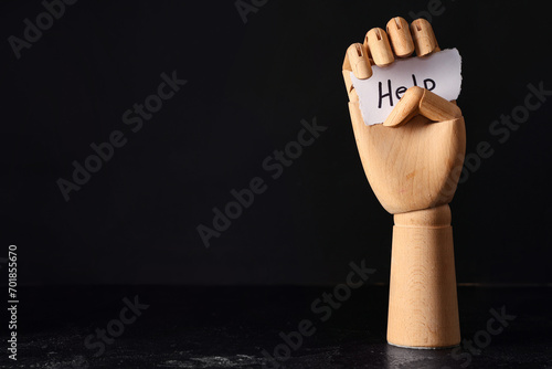 Wooden hand and paper piece with word HELP on dark background. Domestic violence concept