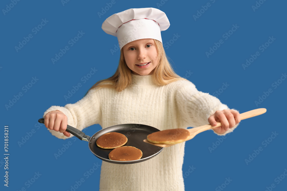 Little chef frying pancakes on blue background