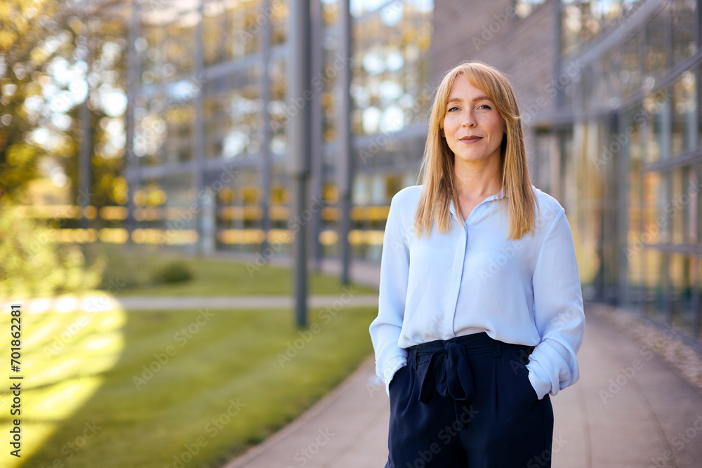 Portrait Of Smiling Businesswoman Standing Outside Modern Office Building