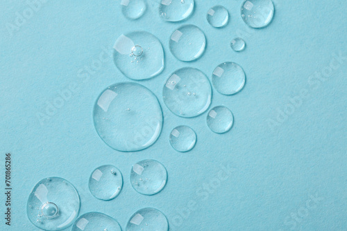 Drops of cosmetic serum on light blue background  top view. Space for text