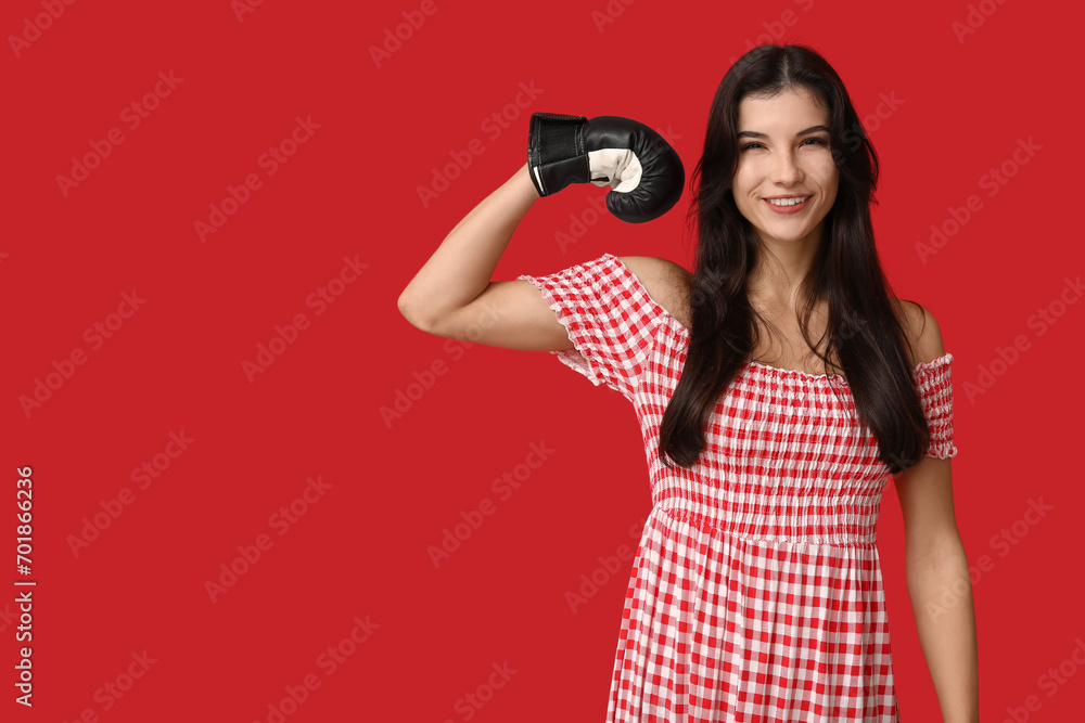 Young woman in boxing gloves on red background. Feminism concept Young woman in boxing gloves on red background. Feminism concept