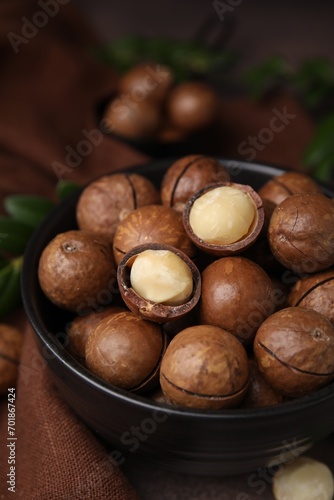 Tasty Macadamia nuts in bowl on table, closeup
