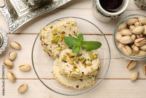 Tasty halva with pistachios and mint served on wooden table, flat lay