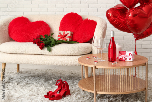 Coffee table with wine bottle, glasses and gift box in living room. Valentine's Day celebration