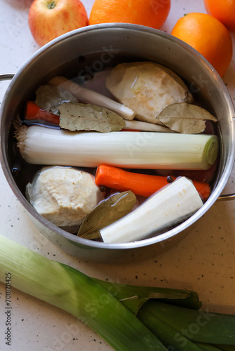 Przygotowywanie domowego rosołu- warzywa (pietruszka, seler, marchew, por) w garnku wraz z przyprawami (liść laurowy, ziele angielskie) photo