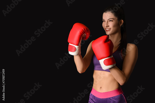 Young female kickboxer on black background